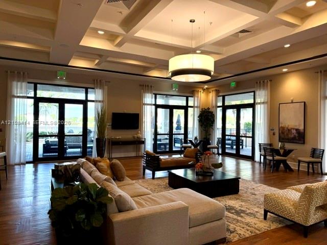 Coffered ceiling, wood-finish flooring, recessed lighting, large drum pendant light, and multiple sets of glass-paned double doors