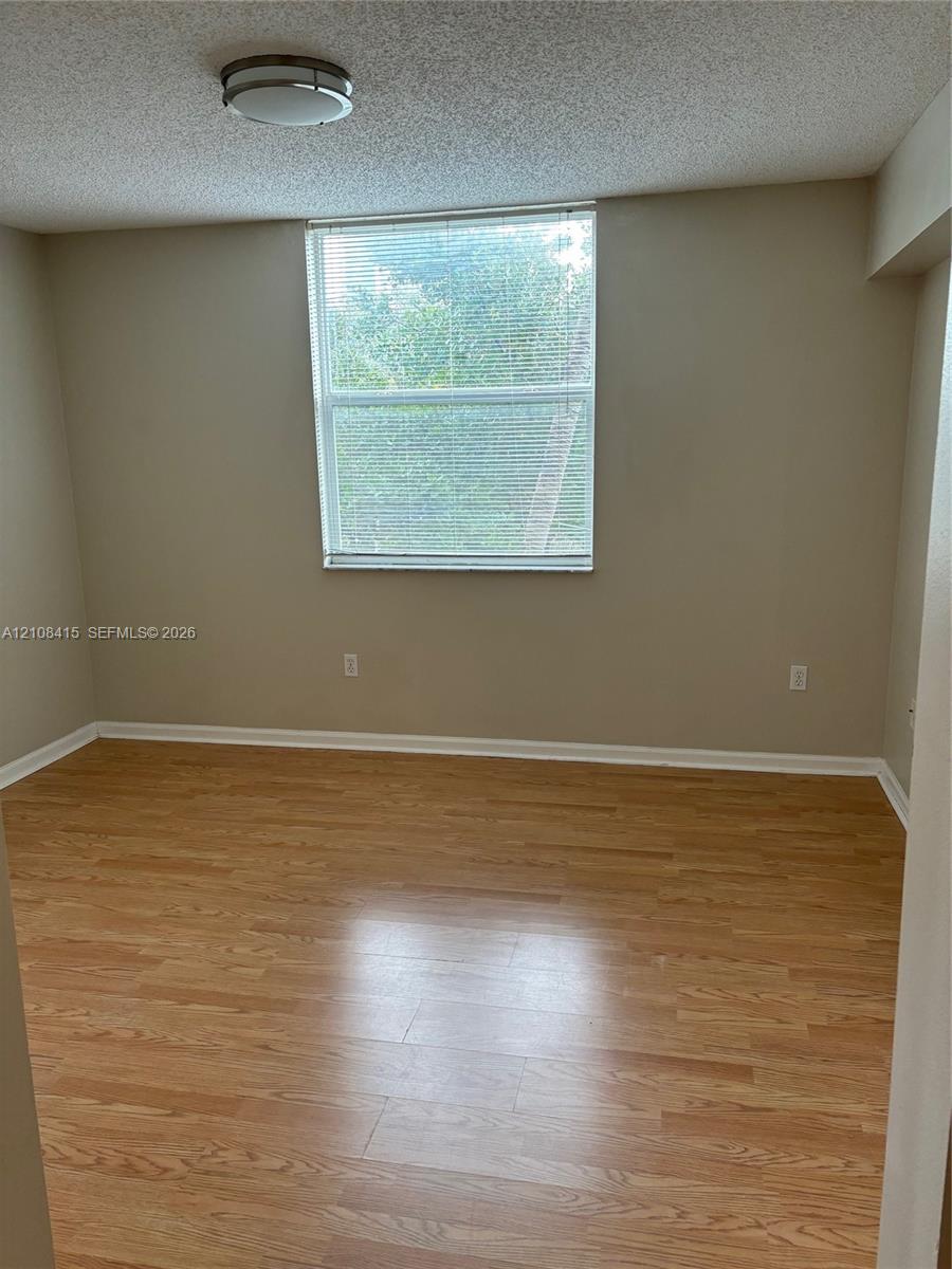 Neutral-toned walls, wood-finish flooring, and a single-pane window with horizontal blinds and integrated flush-mount lighting