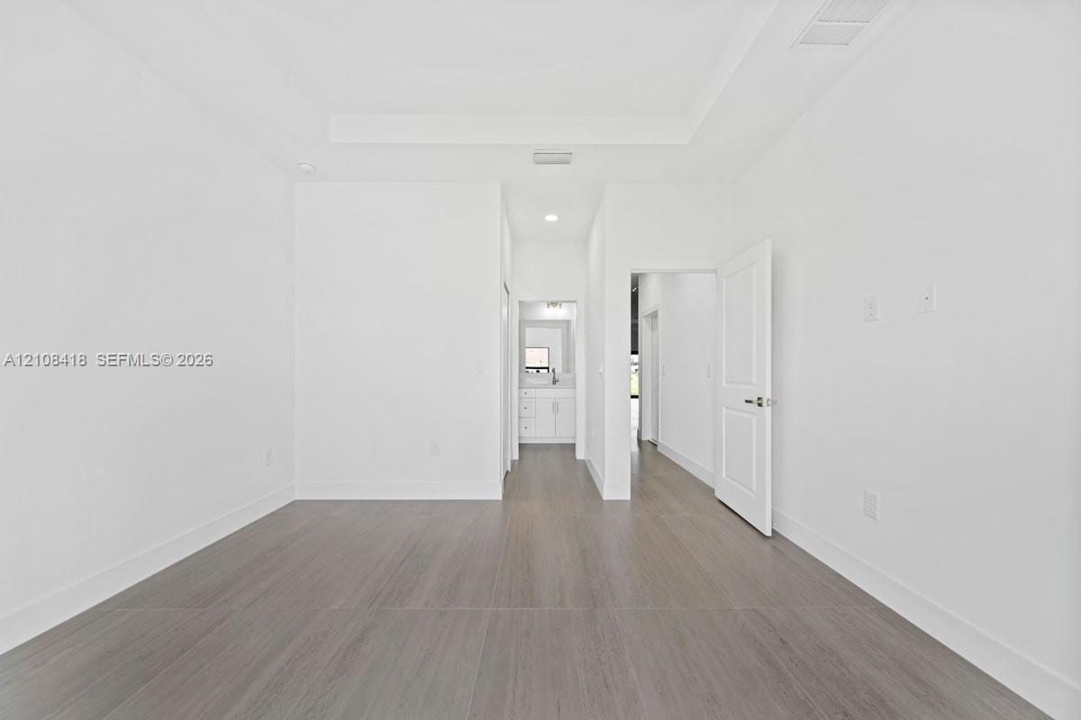 Tray ceiling, wood-finish flooring, recessed lighting, and white multi-panel interior door