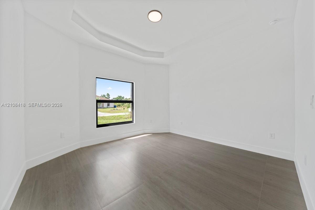 Interior space featuring tray ceilings, wood-finish tile flooring, and a single-pane window with dark trim