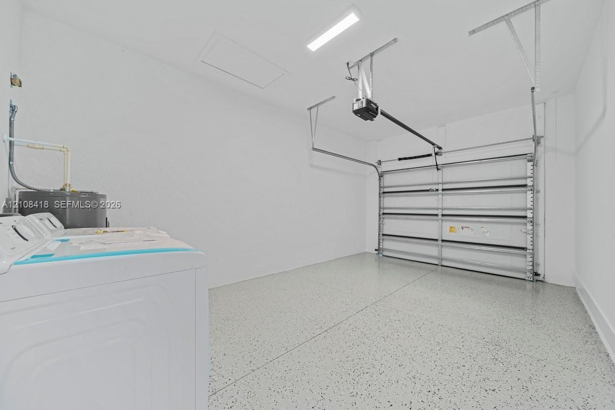 Garage space featuring an epoxy-coated floor, a metal sectional garage door, an automated overhead door opener, and a wall-mounted water heater