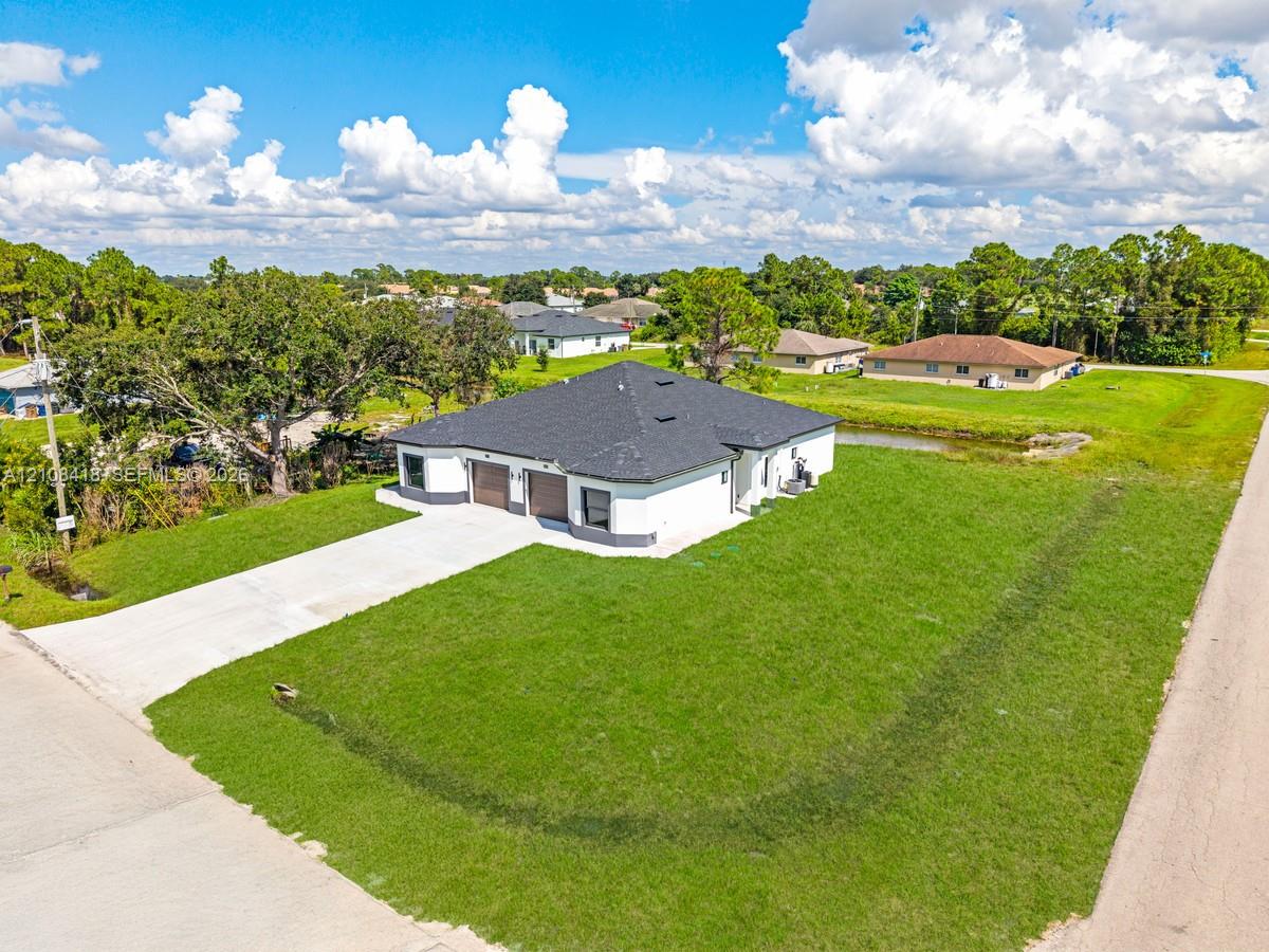 Single-story residence featuring a hipped roof, attached two-car garage, concrete driveway, and expansive lawn area