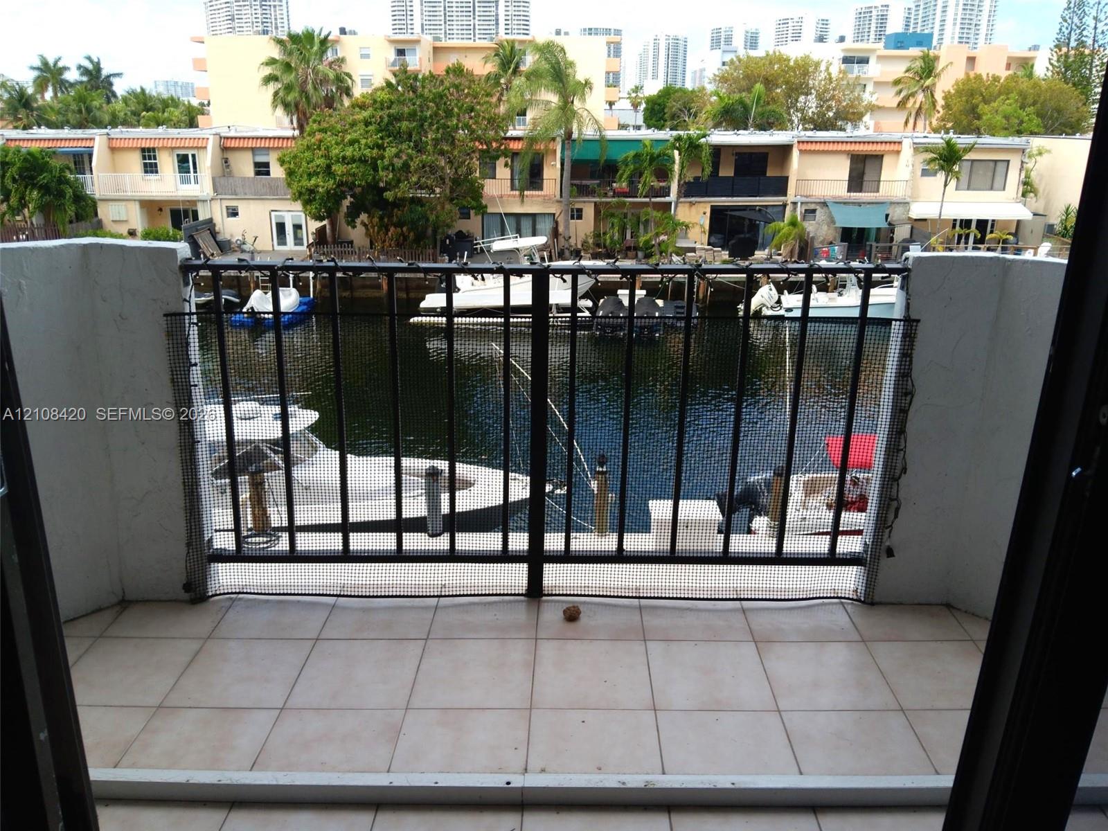Private balcony featuring neutral ceramic tile flooring and a black metal railing overlooking a deep-water canal