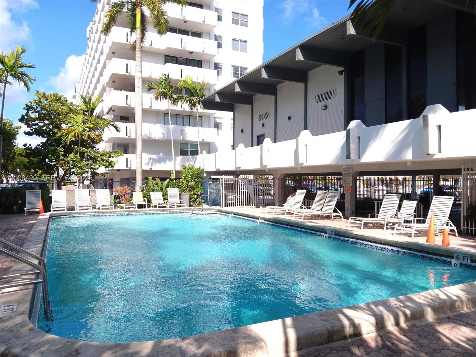 Swimming pool with concrete decking, metal handrails, and surrounding landscaping
