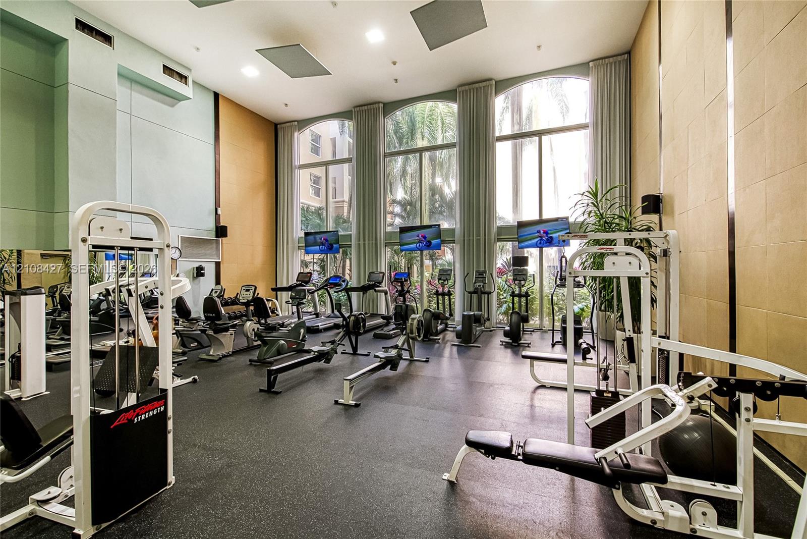 Fitness center featuring floor-to-ceiling arched windows, high ceilings, recessed lighting, and rubberized flooring