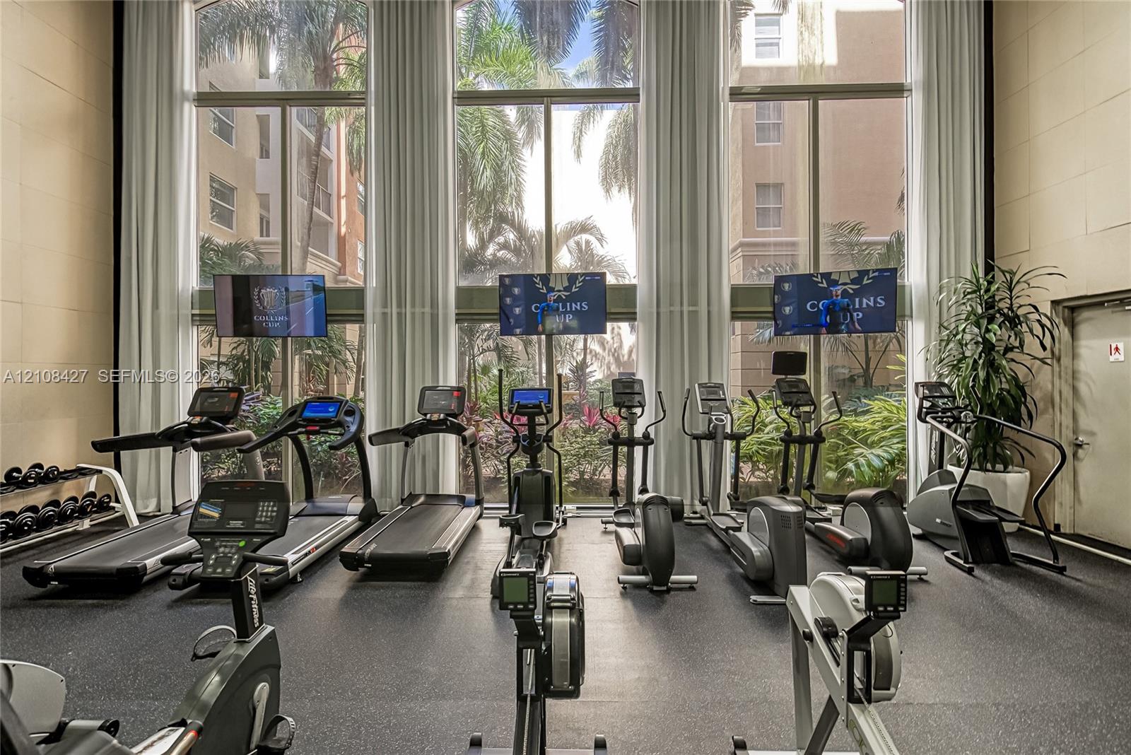 Fitness center featuring floor-to-ceiling windows, high ceilings, and rubberized flooring