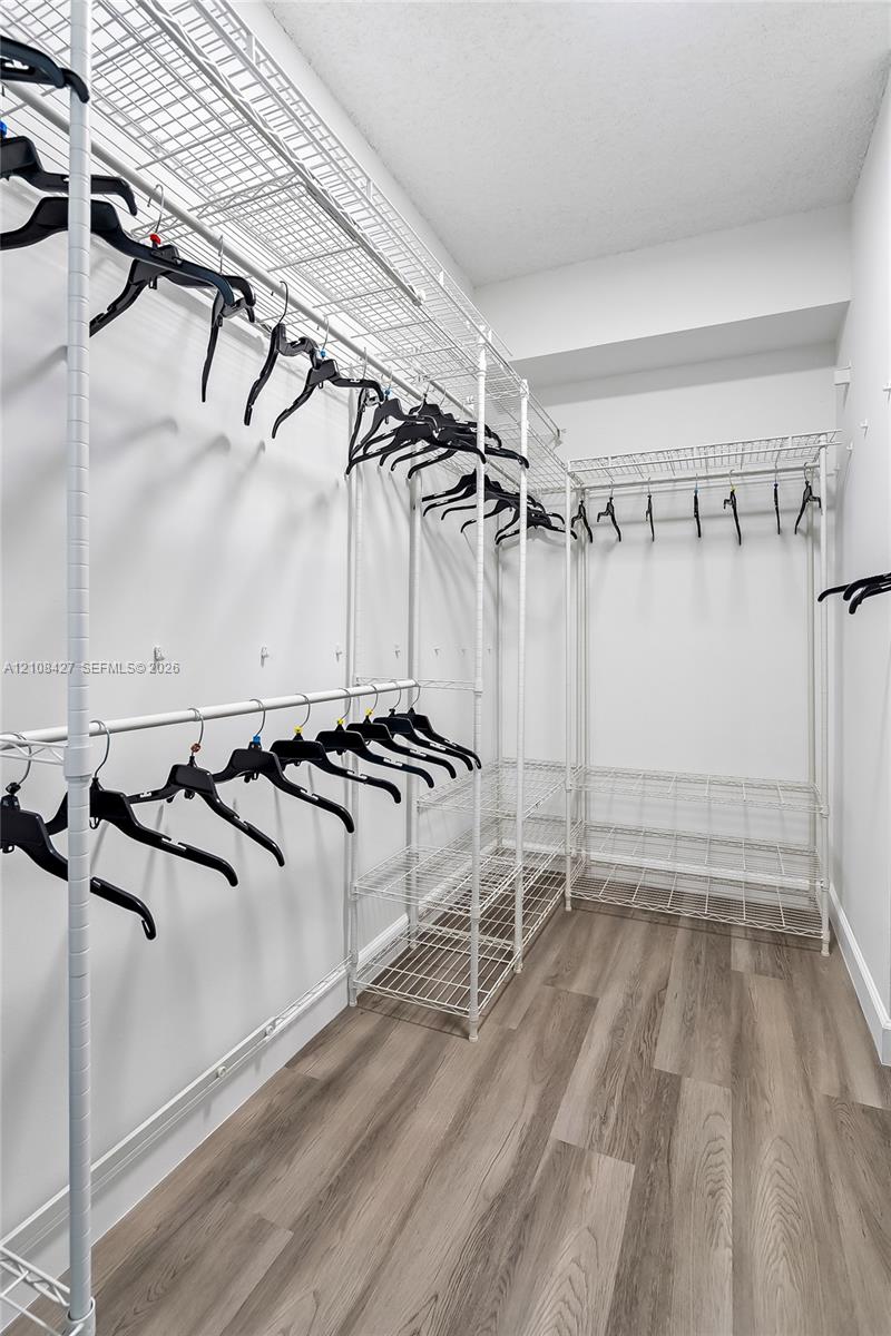 Walk-in closet featuring wood-finish flooring and white wire-grid shelving
