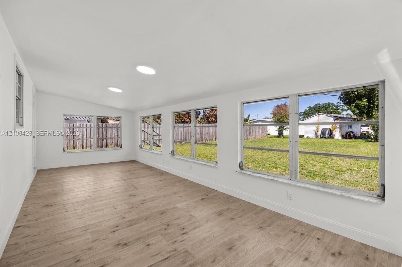 Open-concept interior featuring light wood-finish flooring, recessed lighting, and multiple horizontal sliding windows providing natural illumination