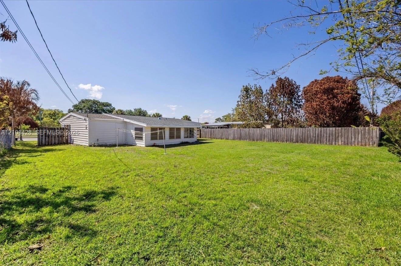 Expansive backyard featuring a large grass lawn and perimeter wood fencing