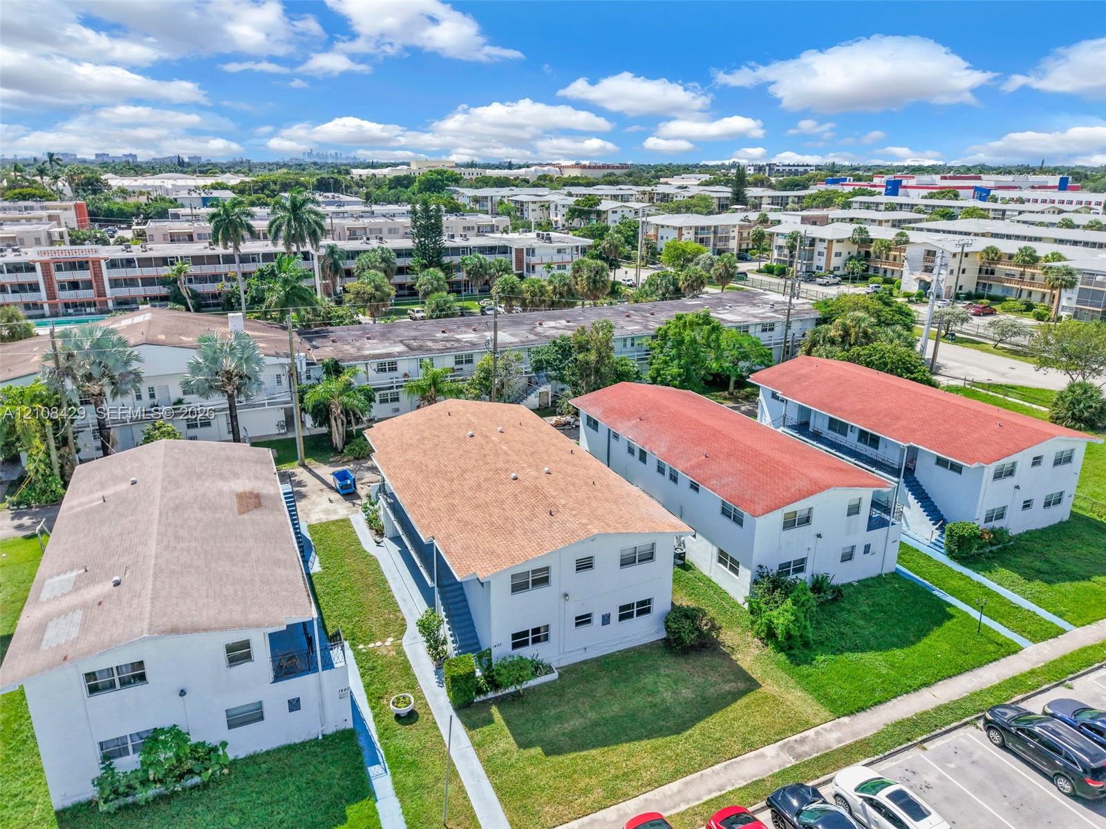 Aerial view of multi-unit residential structures featuring white exteriors, gabled roofs with composition shingles, and integrated concrete walkways