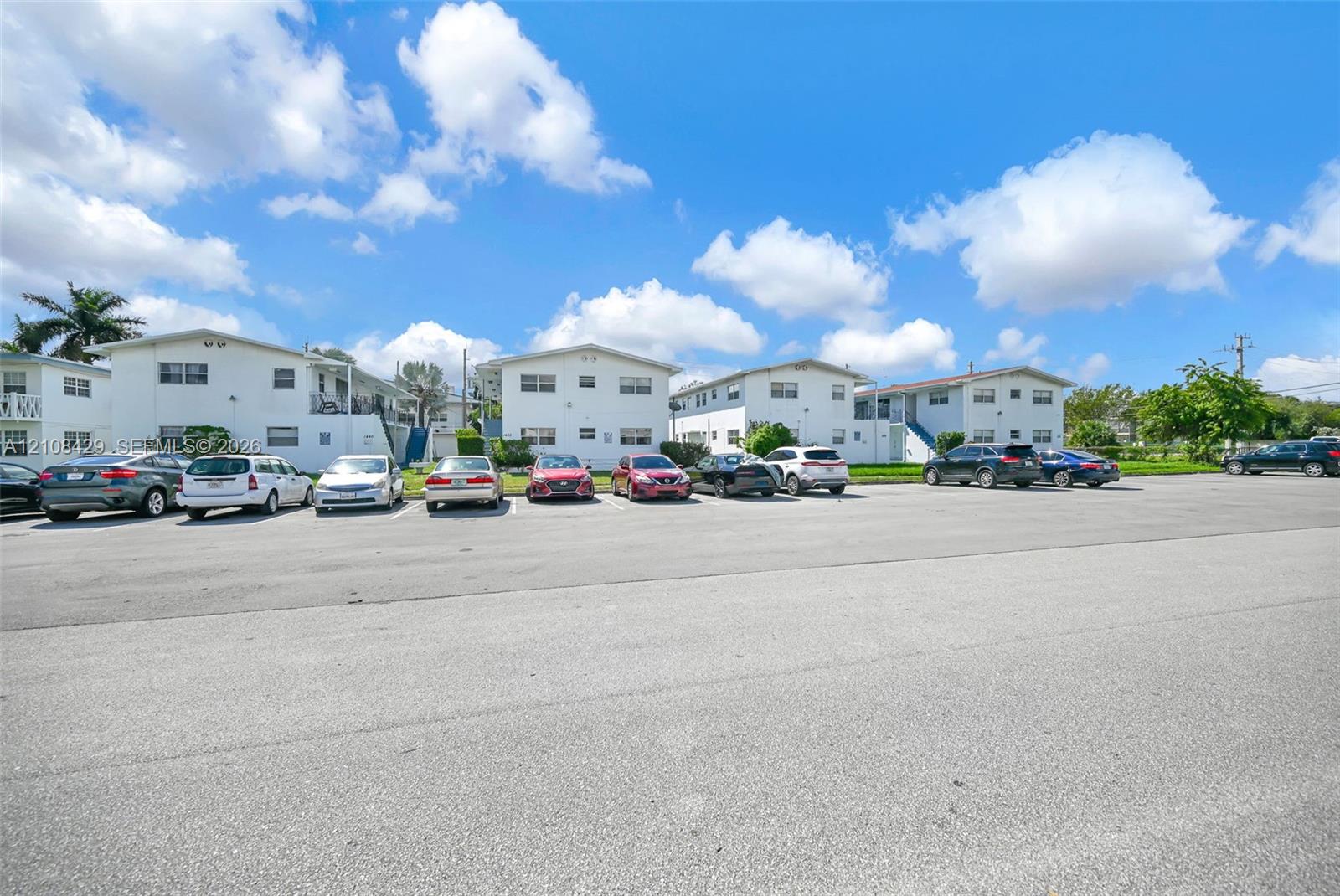 Multi-family residential complex featuring white stucco exteriors, low-pitch roofs, and dedicated asphalt surface parking