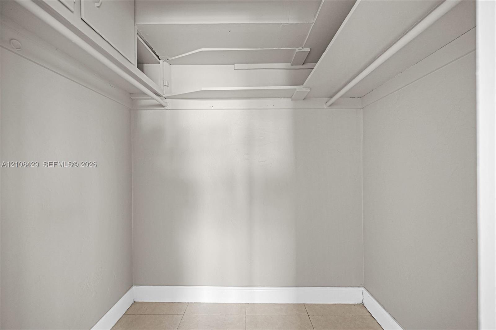 Storage space featuring tiled flooring, built-in shelving, and dual hanging rods