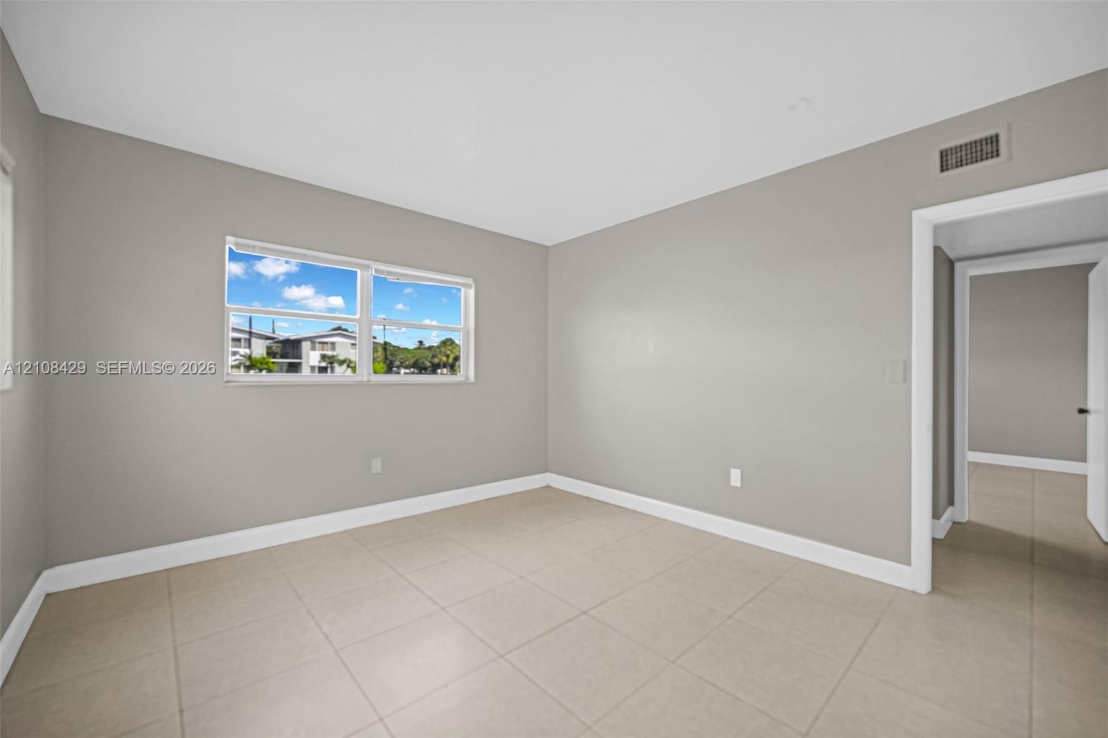 Neutral-toned interior featuring large-format ceramic tile flooring, soft grey wall finishes, and a dual-pane horizontal sliding window