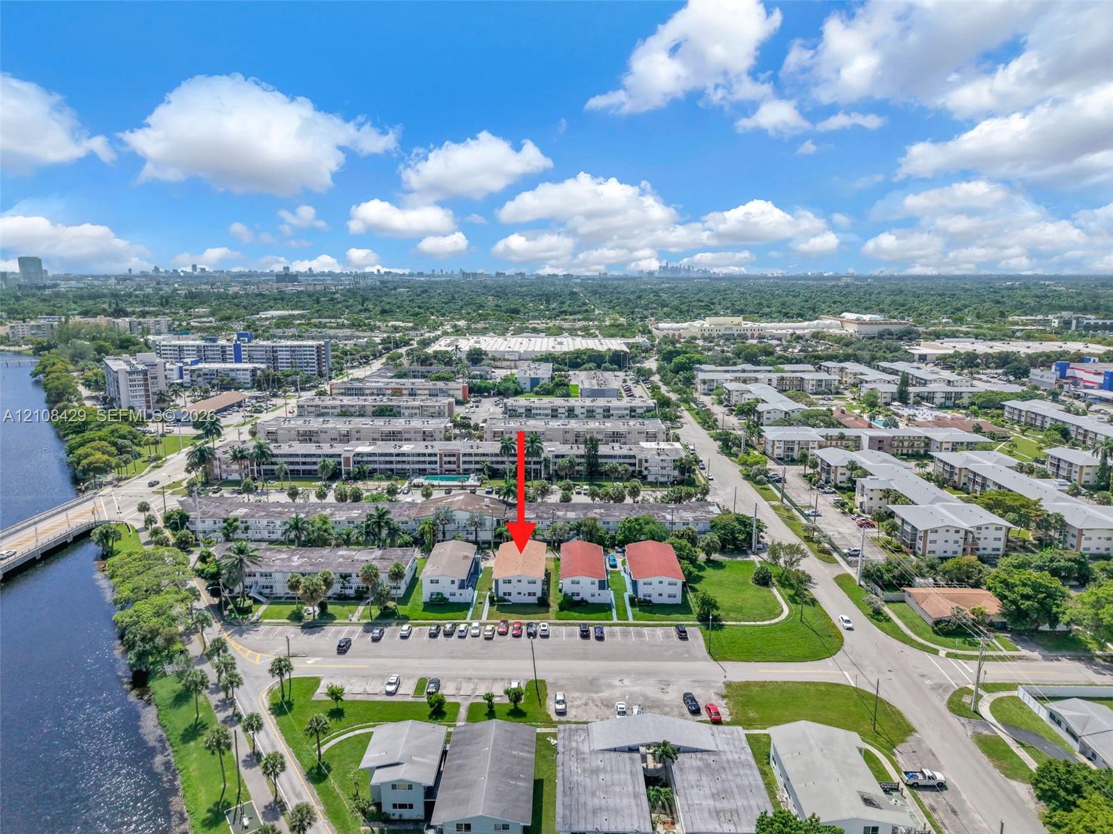 Aerial perspective of multi-family property featuring a terracotta-toned roof, surface parking, and proximity to the waterfront