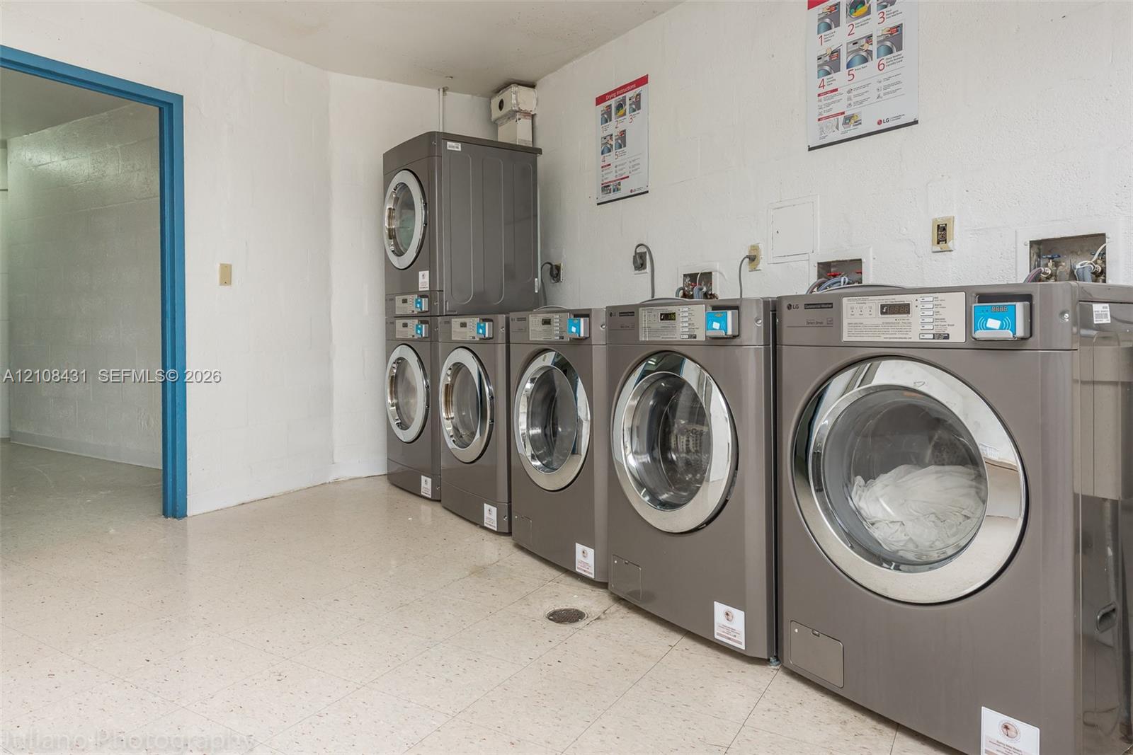 Dedicated laundry facility featuring five front-loading machines and tile flooring