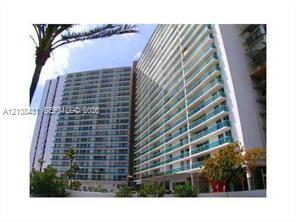 High-rise residential exterior featuring expansive glass-railed balconies and floor-to-ceiling windows