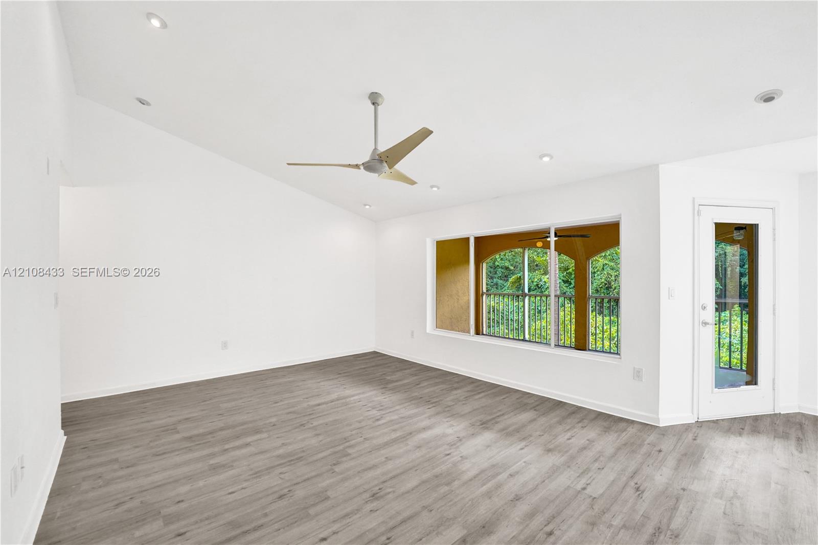 Vaulted ceilings featuring recessed lighting, wood-finish flooring, a contemporary ceiling fan, and a glass-paneled exterior door