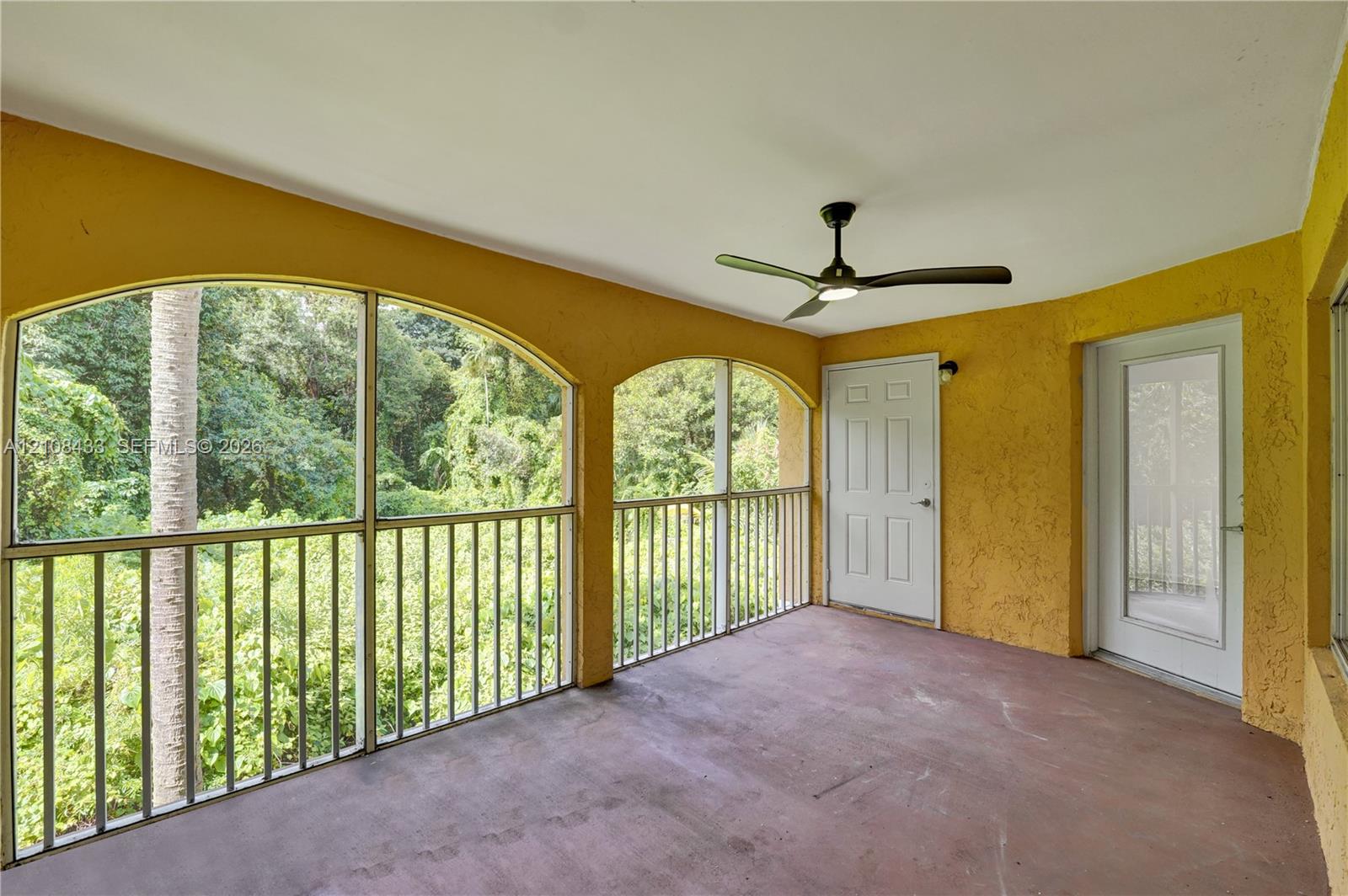 Covered porch featuring arched screened enclosures, solid surface flooring, and a ceiling fan