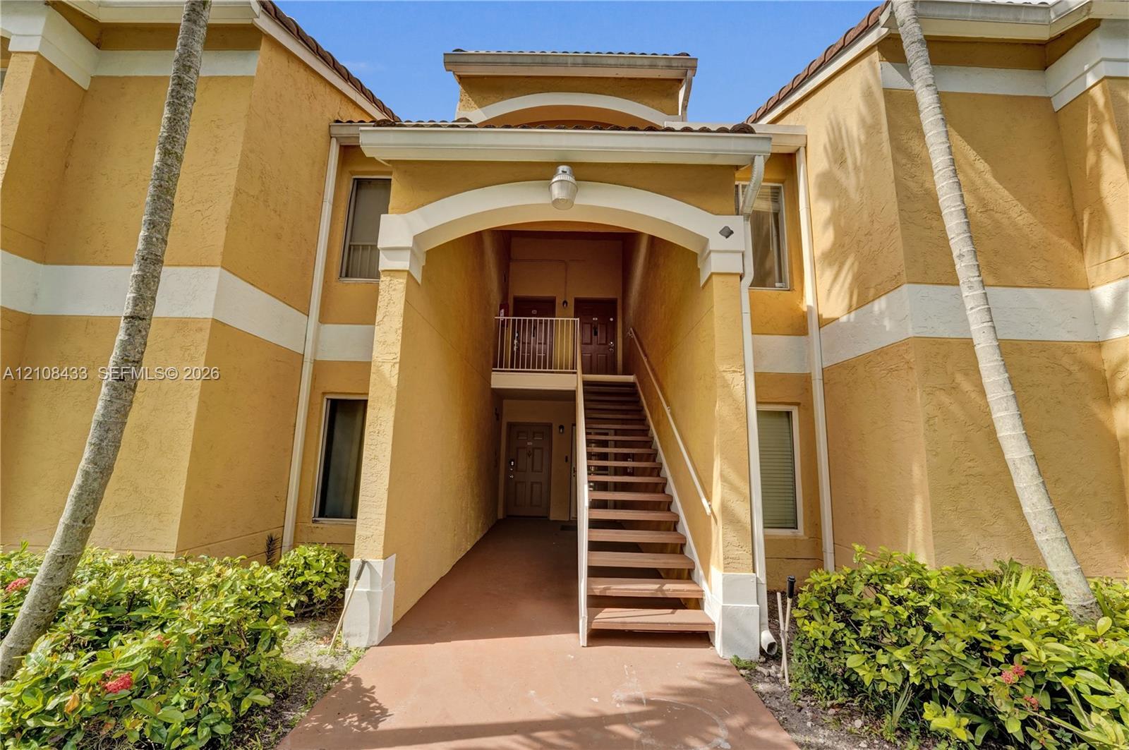 Stucco exterior featuring an arched entryway, decorative trim, tiled roofline, and exterior staircase Stucco exterior featuring an arched entryway, decorative trim, tiled roofline, and exterior staircase