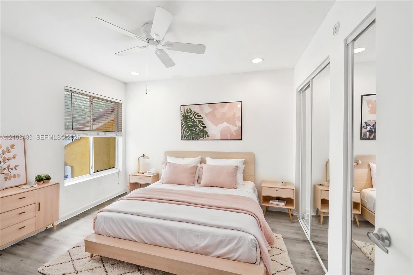Bright room featuring wood-finish flooring, recessed lighting, a ceiling fan, and sliding mirrored closet doors