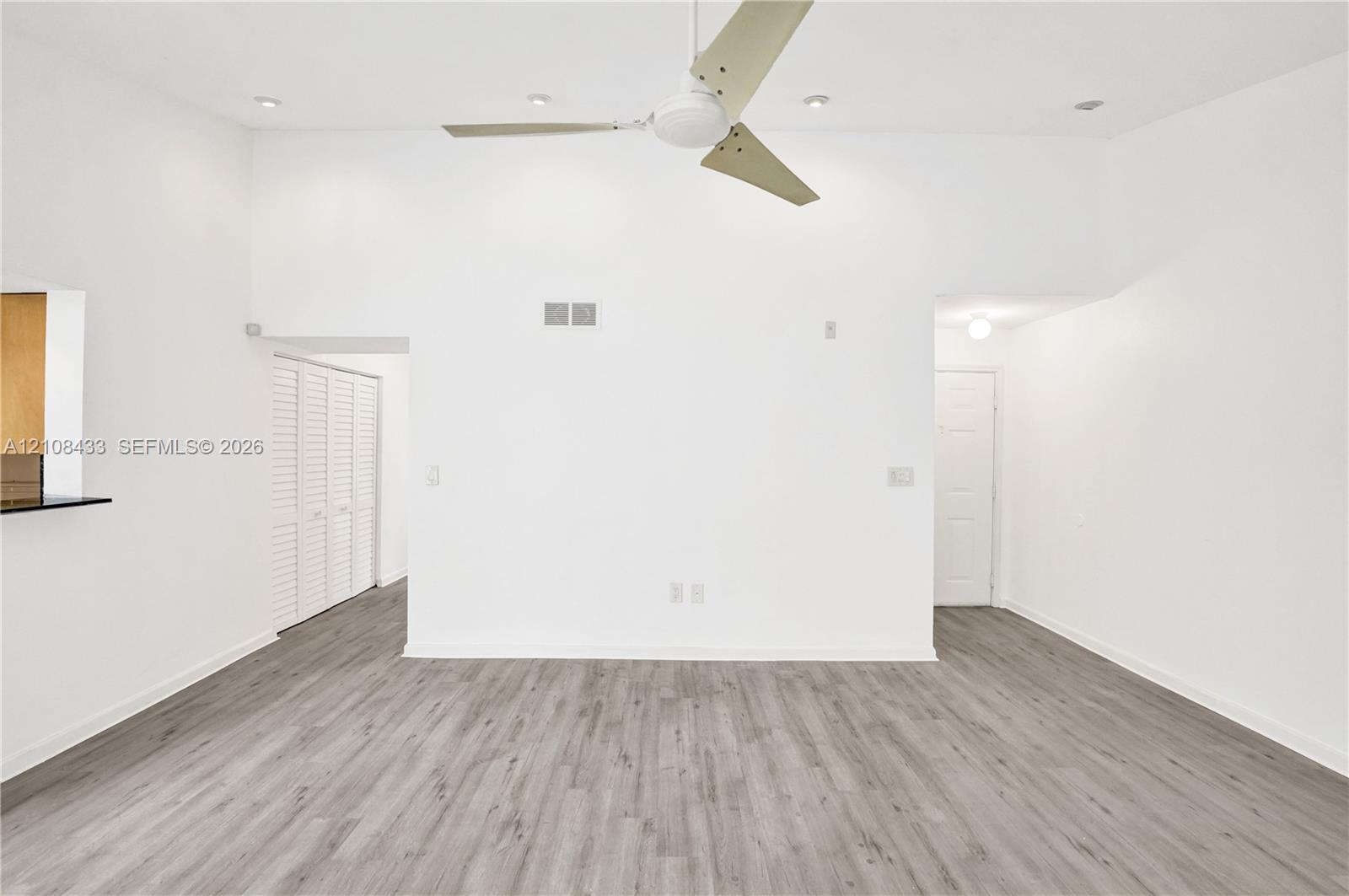 High ceilings featuring a central ceiling fan, recessed lighting, wood-finish flooring, and white louvered closet doors