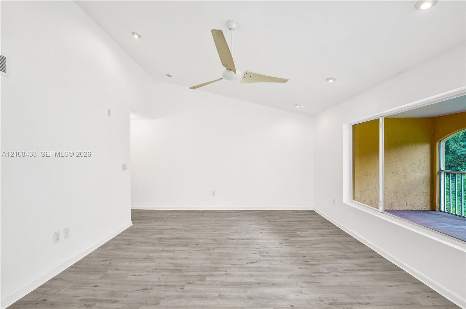 Vaulted ceiling with recessed lighting, wood-finish flooring, and a modern three-blade ceiling fan