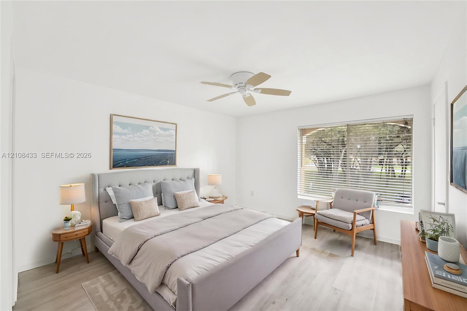 Light-filled room featuring wood-finish flooring, a white ceiling fan, and a large window