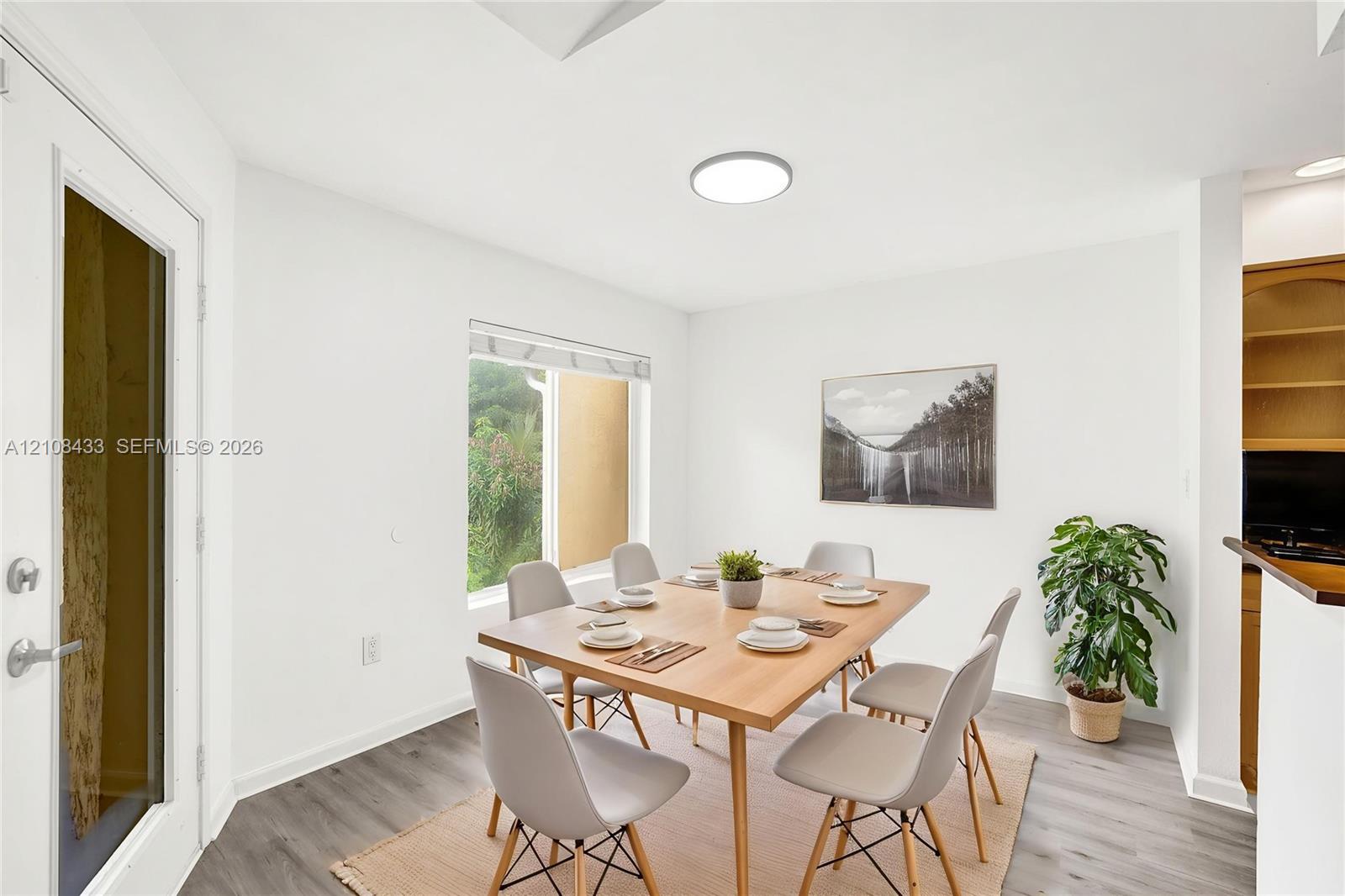 Dining area featuring wood-finish flooring, a flush-mount circular light fixture, a large window, and built-in wooden shelving