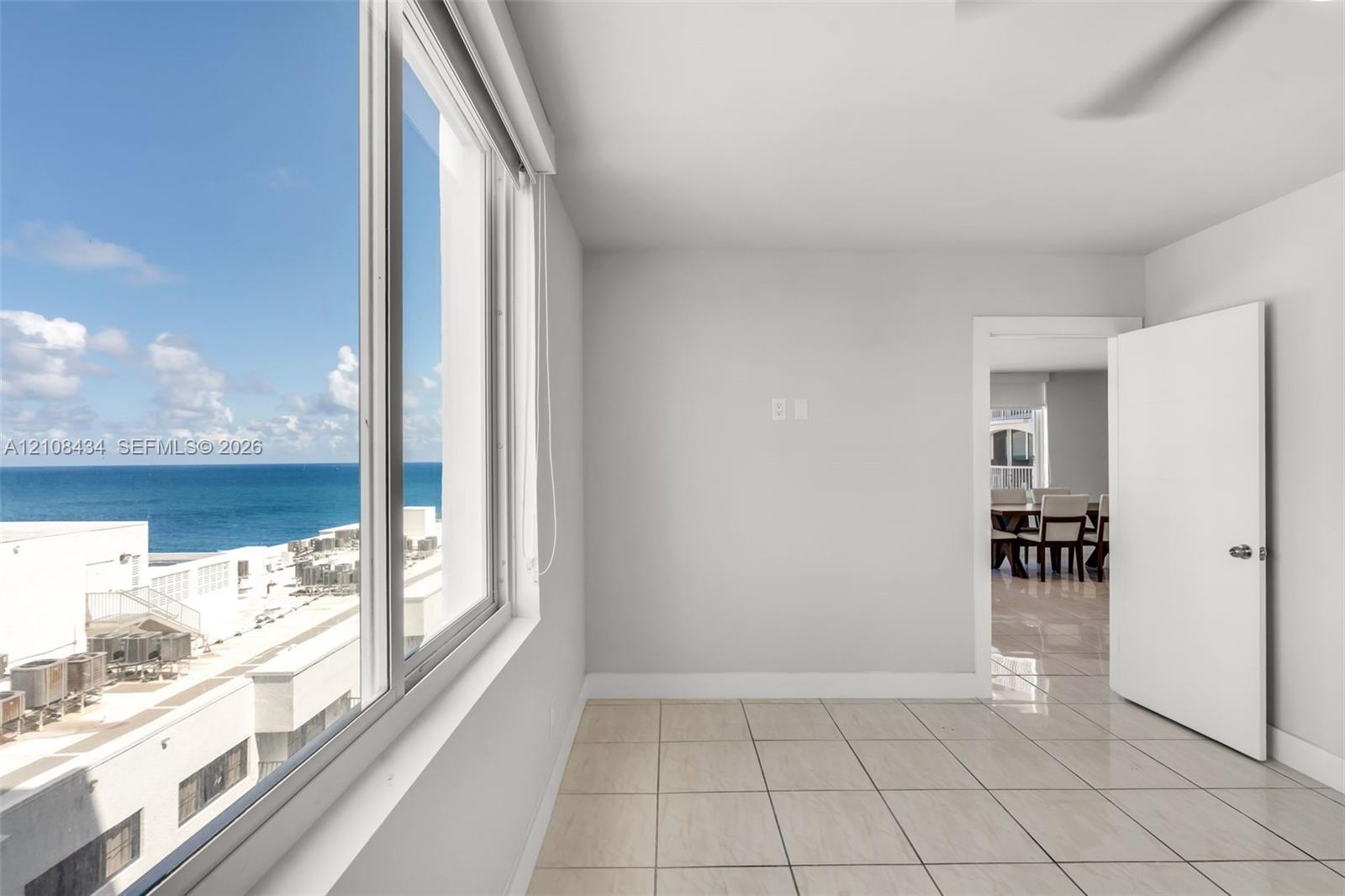 Large-format windows providing ocean scenery, neutral wall finishes, tile flooring, and a solid-core interior door