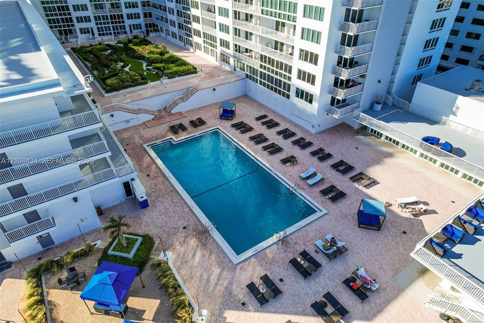 Outdoor swimming pool featuring a paved pool deck and multi-level landscaped gardens