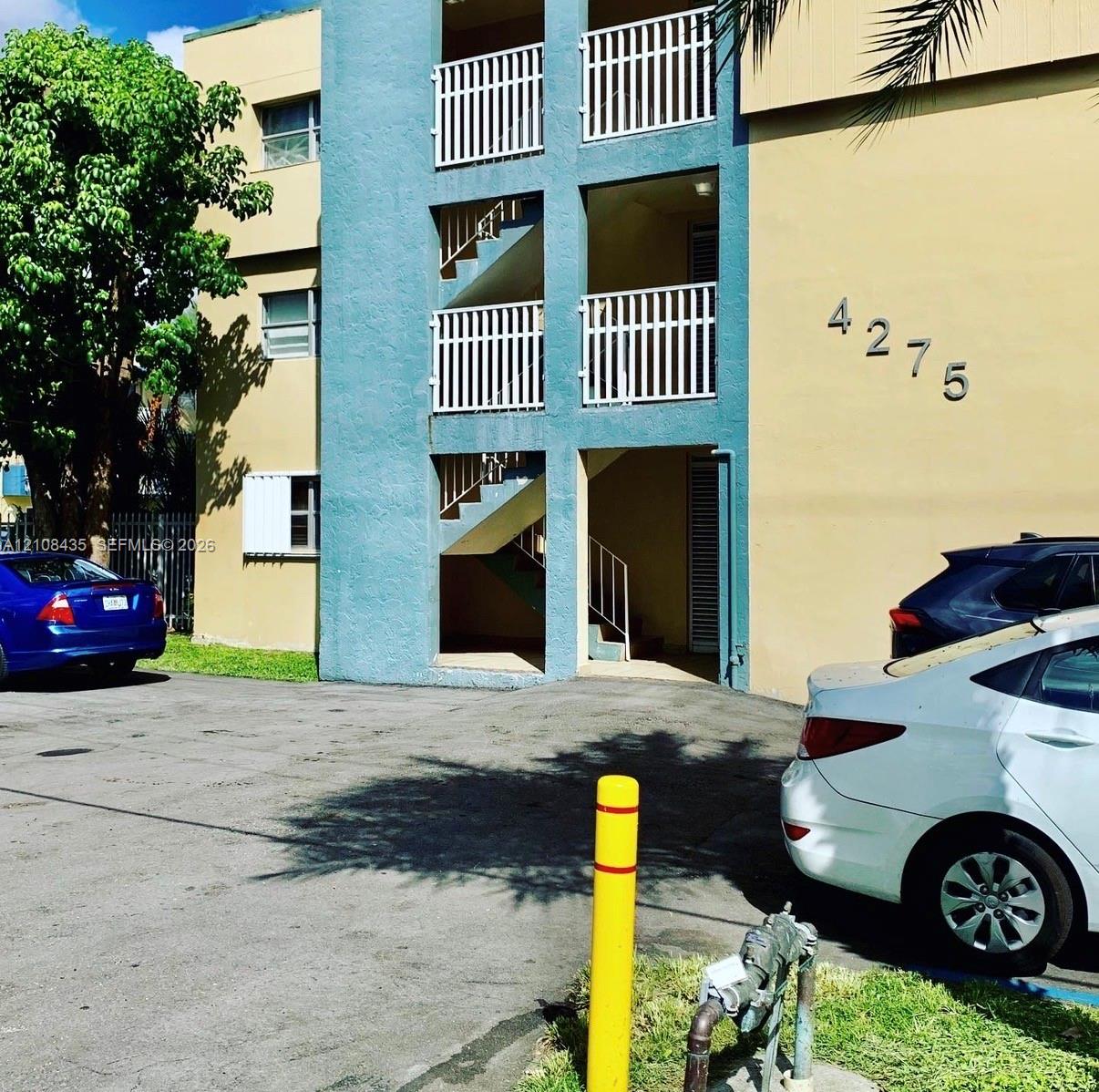 Multi-story exterior featuring a stucco facade, white metal balcony railings, and exterior staircases