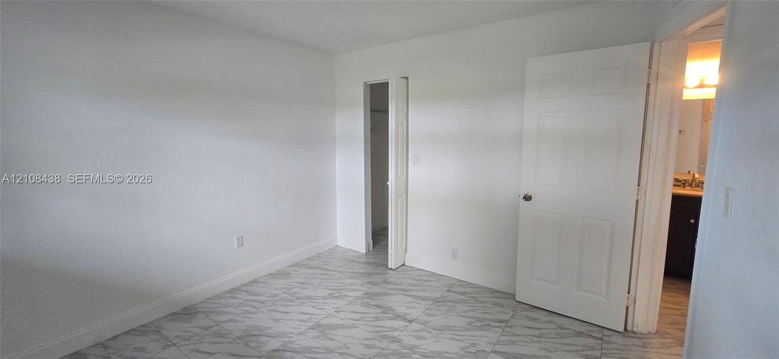 Neutral-toned interior space featuring stone-finish flooring and a walk-in closet with bifold door