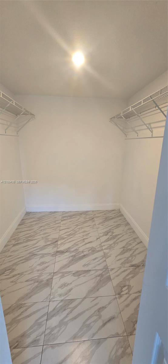 Walk-in closet featuring large-format tile flooring and dual-level wire shelving