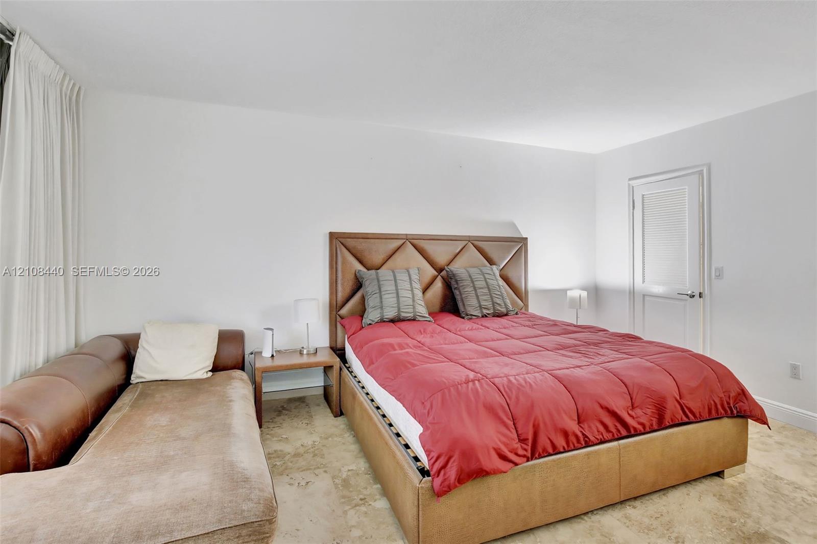 Neutral-toned stone flooring and a white paneled door with a brushed-metal lever handle