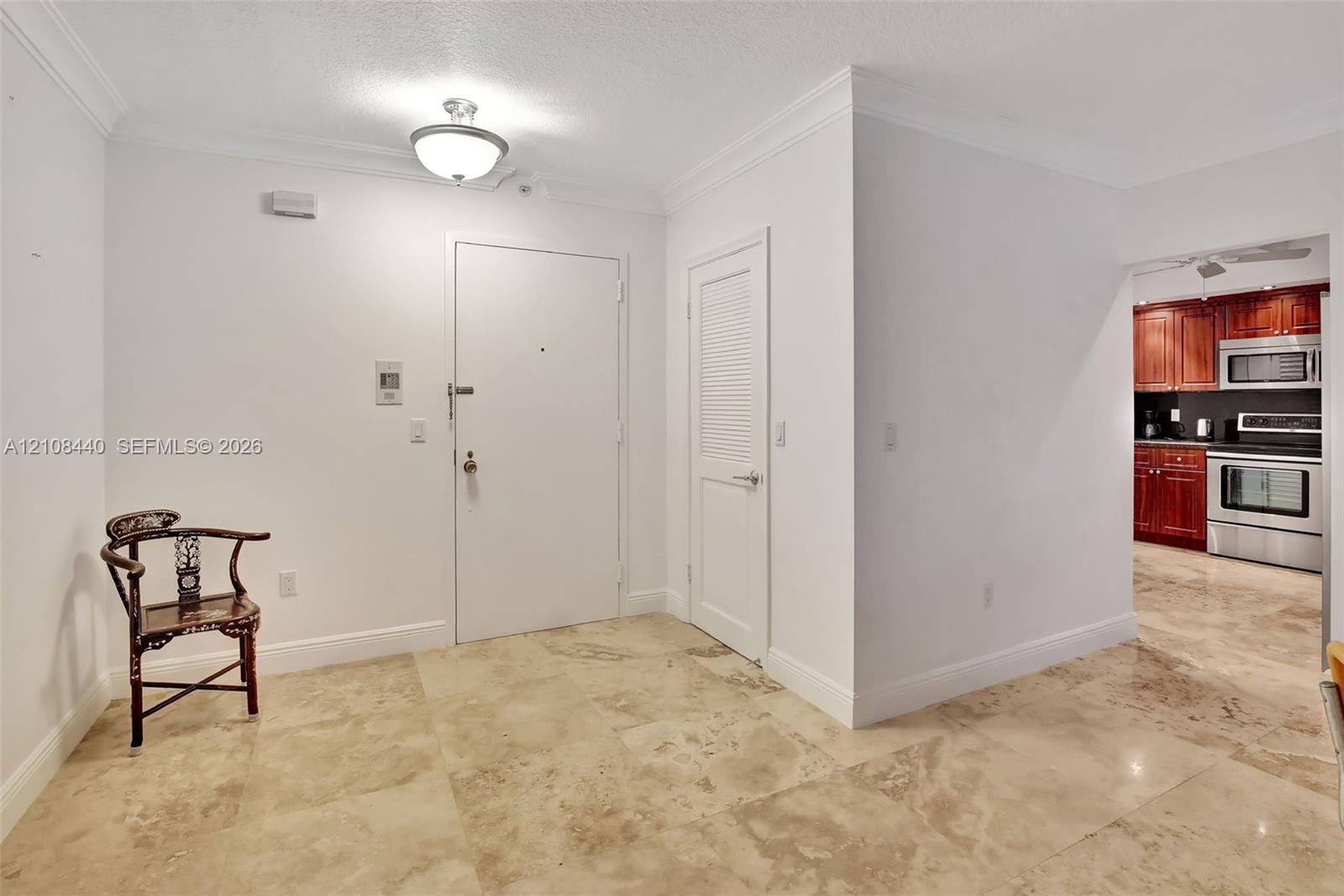 Neutral-tone tile flooring, crown molding, semi-flush mount ceiling light, and louvered-panel door Neutral-tone tile flooring, crown molding, semi-flush mount ceiling light, and louvered-panel door