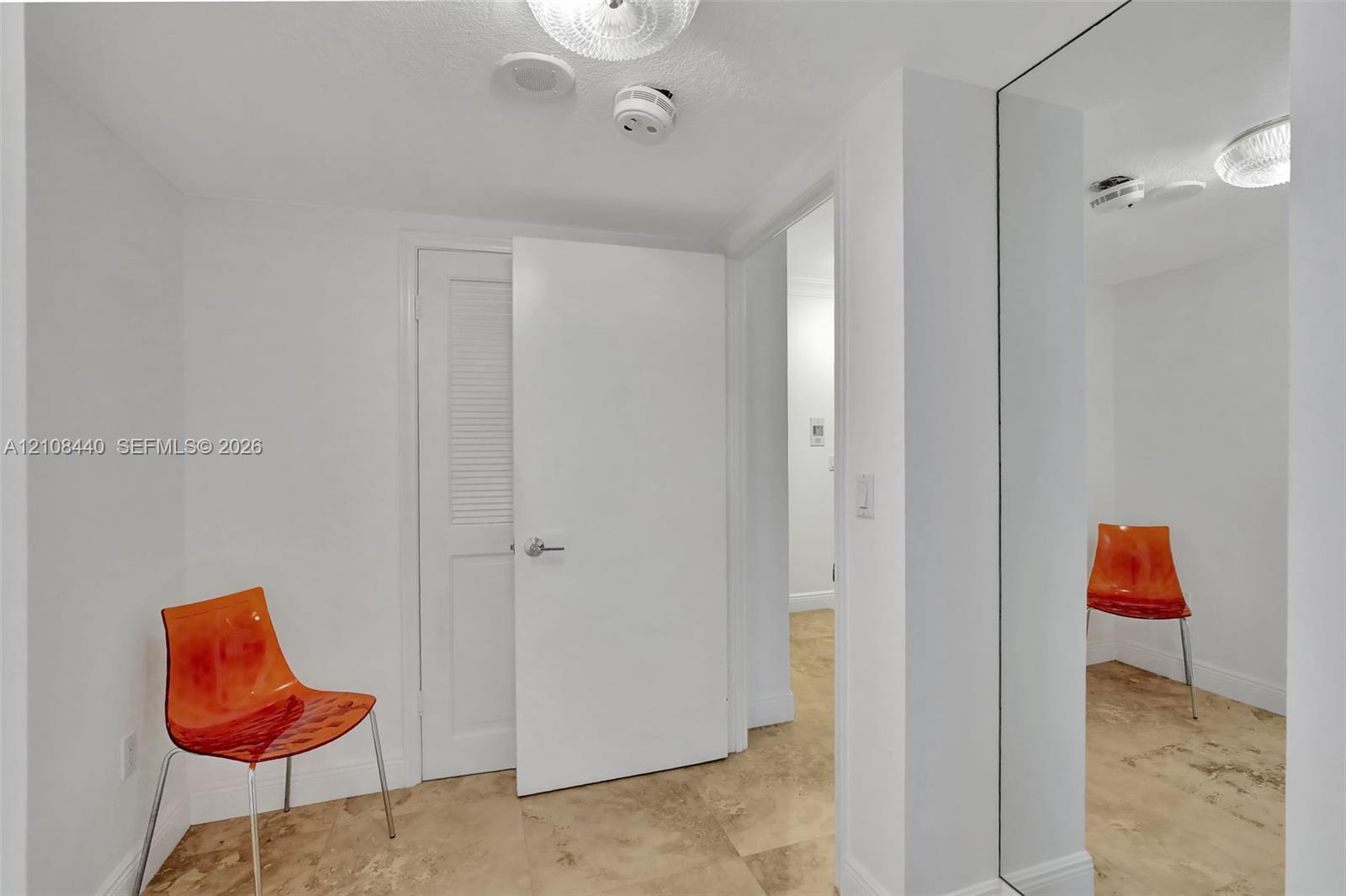 Interior space featuring stone tile flooring, full-height wall mirror, and a louvered closet door