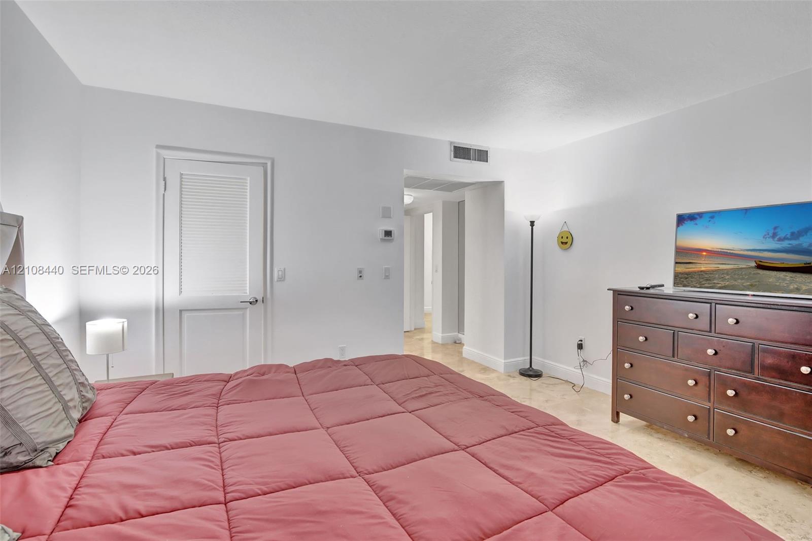 Neutral interior space featuring polished stone flooring, a single-panel interior door with louvered detail, and smooth-finish walls