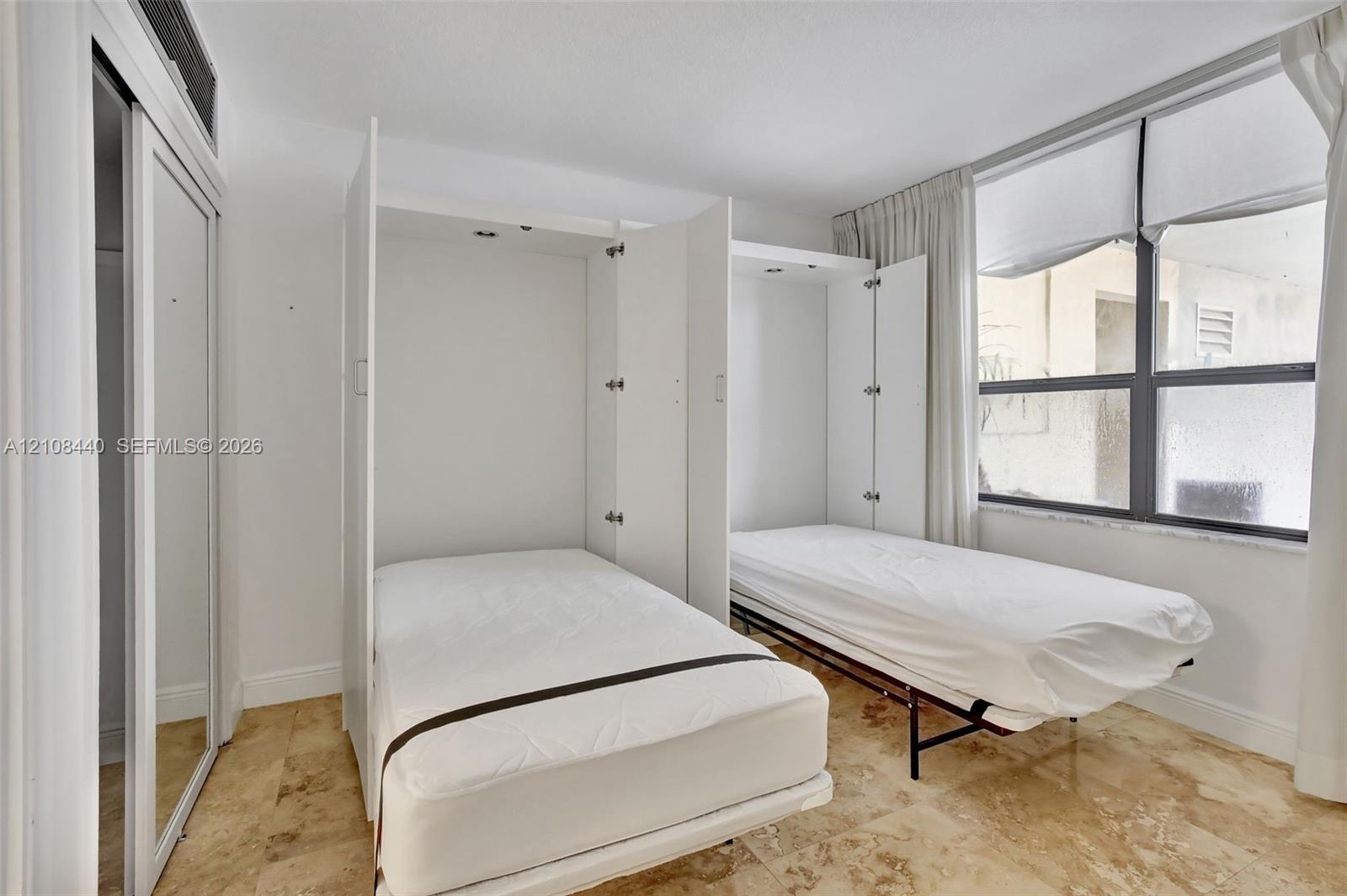 Built-in dual wall-mounted beds, stone-finish flooring, and sliding-door closets with mirrored panels