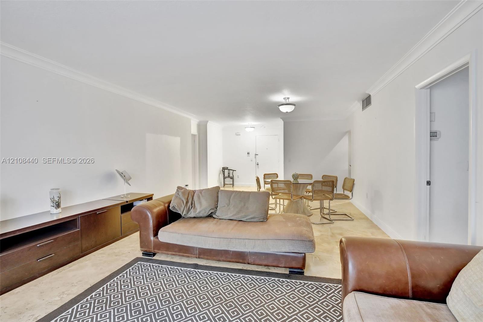 Neutral-toned stone flooring, crown molding, and recessed ceiling lighting throughout Neutral-toned stone flooring, crown molding, and recessed ceiling lighting throughout