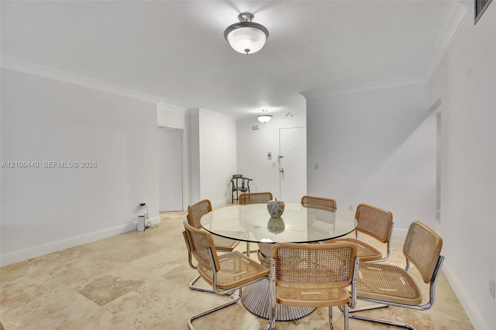 Neutral-toned natural stone flooring, crisp white walls, crown molding, and dual semi-flush mount light fixtures