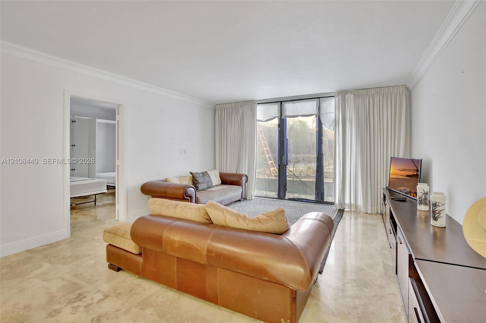 Living space featuring polished stone flooring, crown molding, and floor-to-ceiling glass sliding doors Living space featuring polished stone flooring, crown molding, and floor-to-ceiling glass sliding doors