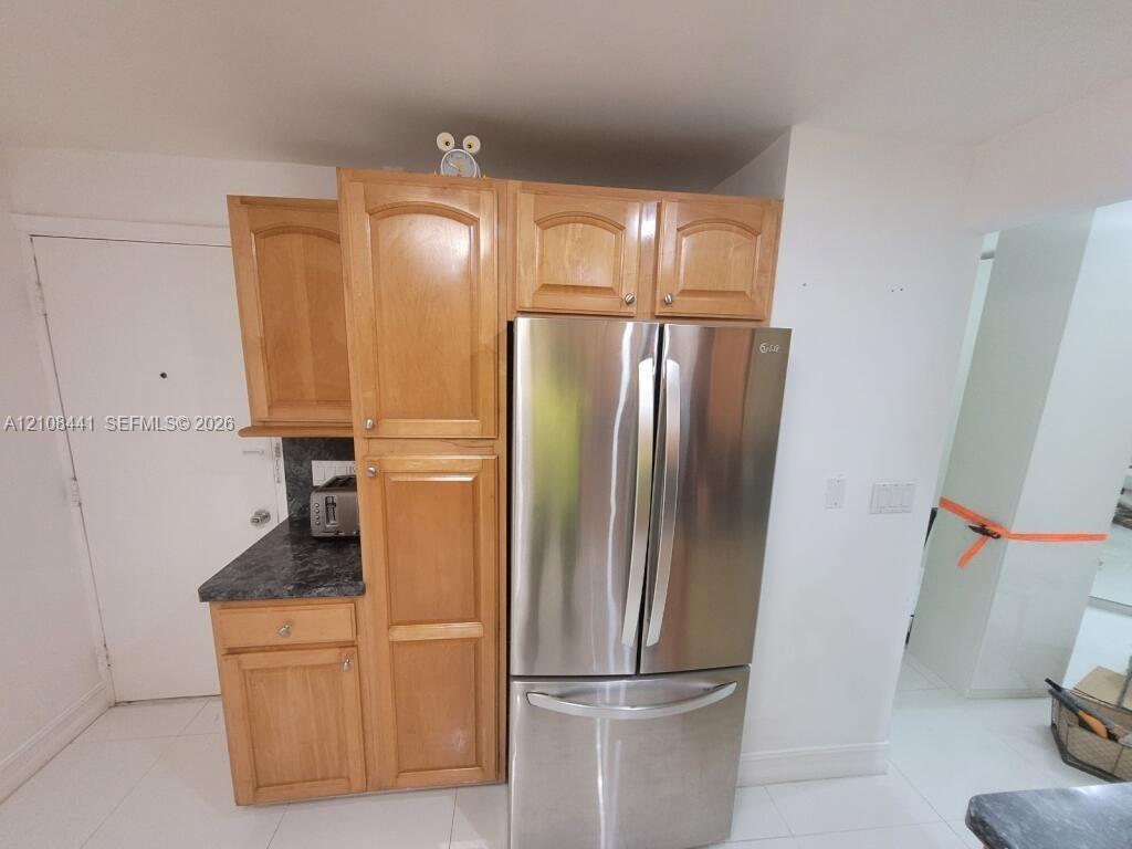 Natural wood cabinetry, stainless steel French-door refrigerator, and dark stone-finish countertops