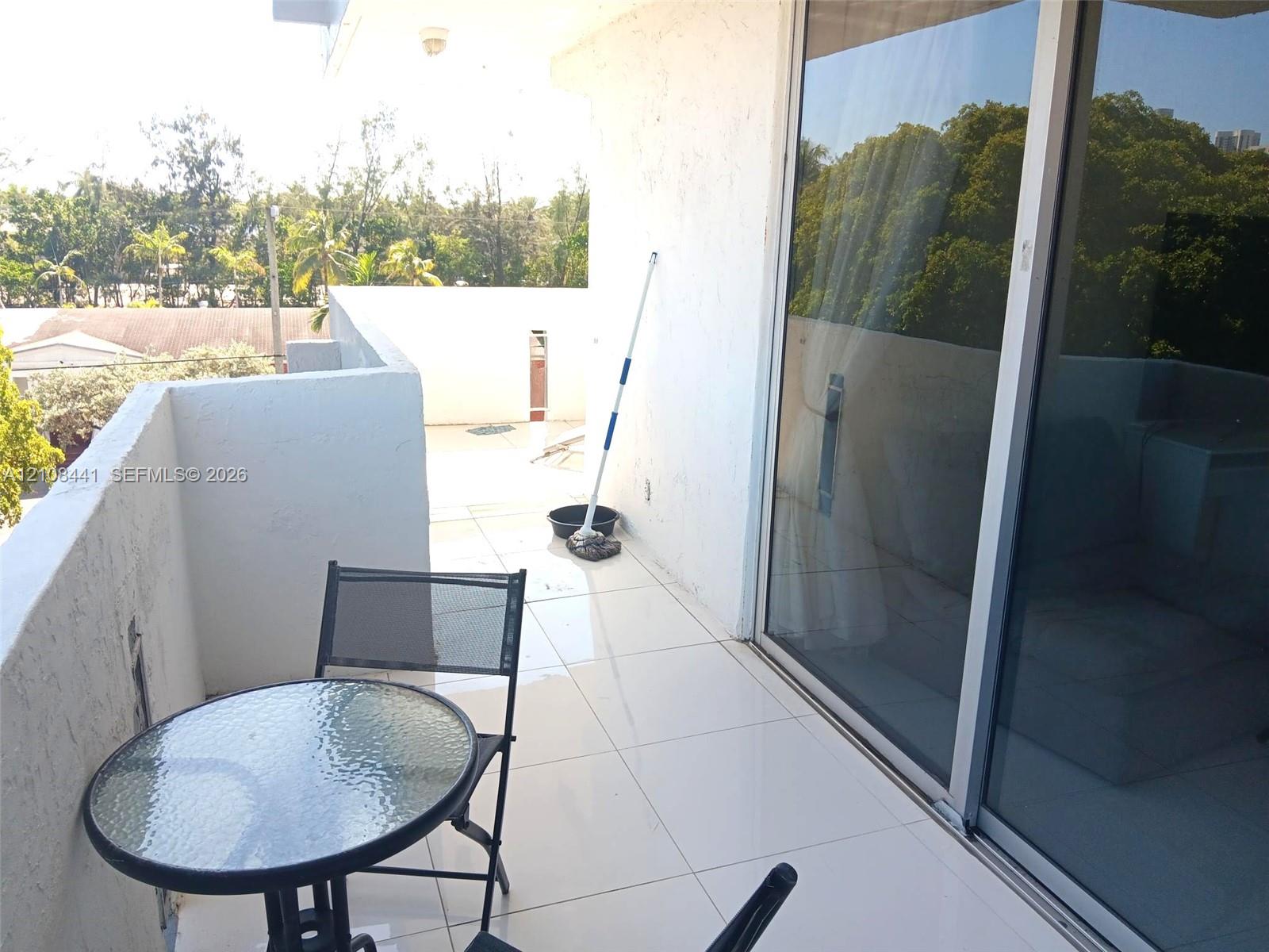 Private balcony featuring large-format tile flooring, textured stucco walls, and sliding glass door entry