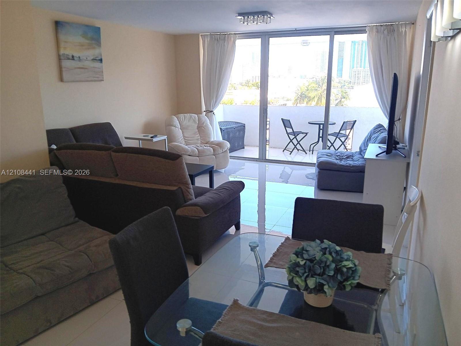 Large-format tile flooring, ceiling-mounted track lighting, and full-height sliding glass doors leading to an exterior balcony