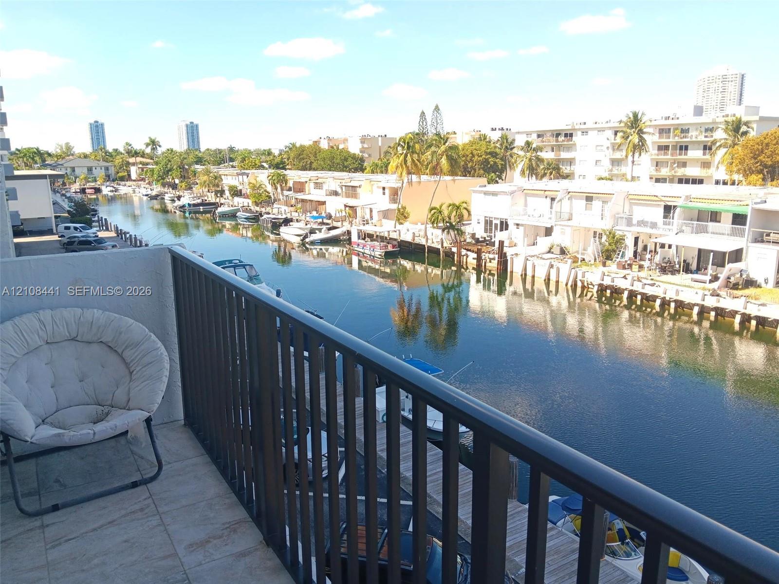 Balcony featuring tile flooring and a metal railing overlooking a canal with boat slips
