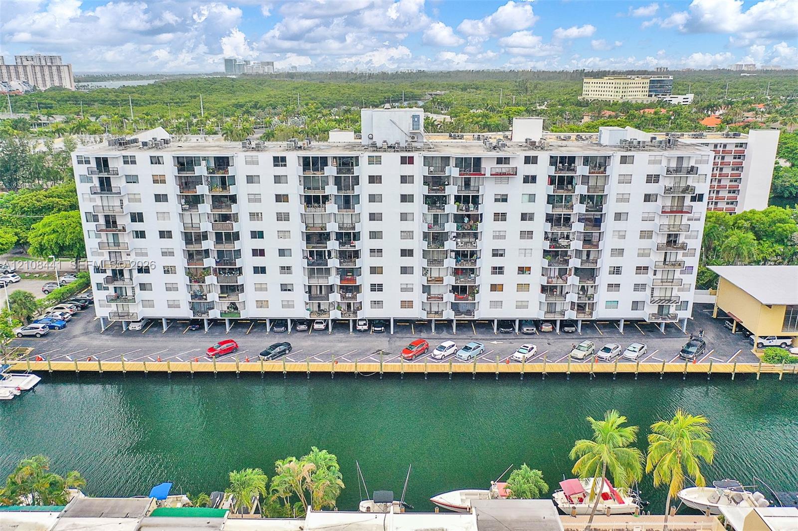 Multi-story residential building featuring private balconies, assigned surface parking, and a waterfront bulkhead with direct canal access