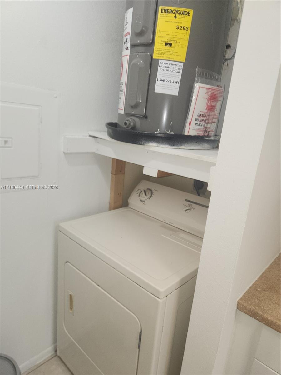Utility closet featuring an electric water heater housed on a support shelf above a clothes dryer Utility closet featuring an electric water heater housed on a support shelf above a clothes dryer