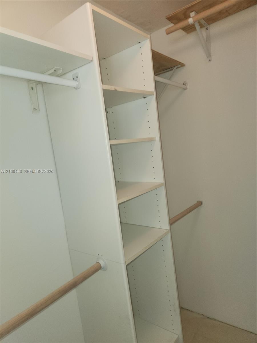 Built-in white storage shelving unit with multiple tiers and dual wooden clothing rods