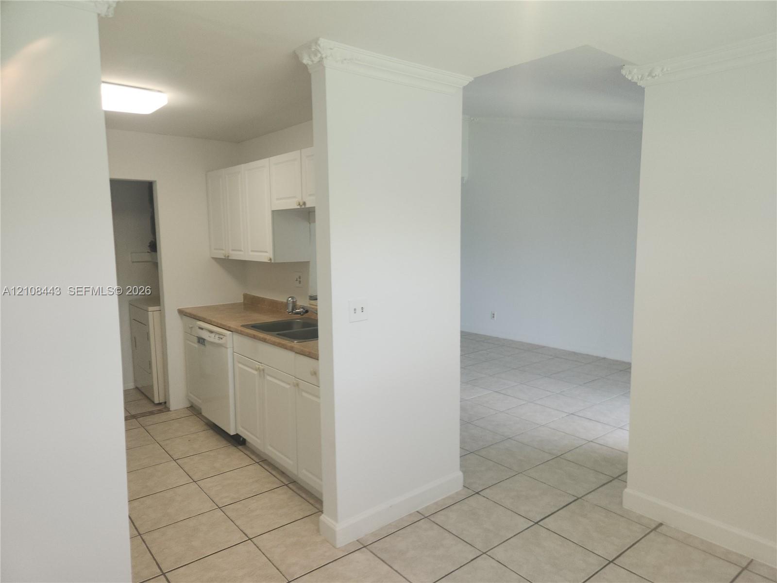 Kitchen featuring white cabinetry, solid-surface countertops, dual-basin stainless steel sink, built-in dishwasher, and ceramic tile flooring throughout Kitchen featuring white cabinetry, solid-surface countertops, dual-basin stainless steel sink, built-in dishwasher, and ceramic tile flooring throughout