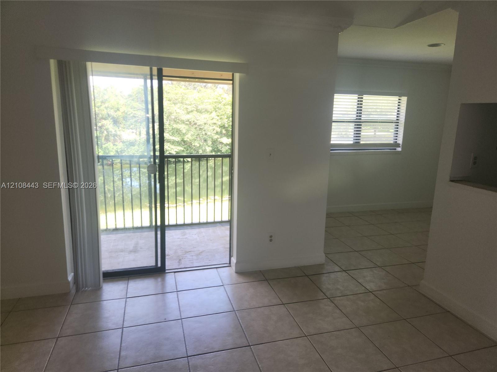 Tile flooring, sliding glass door, and covered balcony with metal railing Tile flooring, sliding glass door, and covered balcony with metal railing